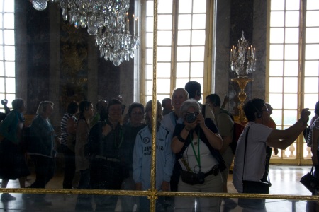 E.g. shoots herself, and the rest of us, in Versailles' Hall of Mirrors